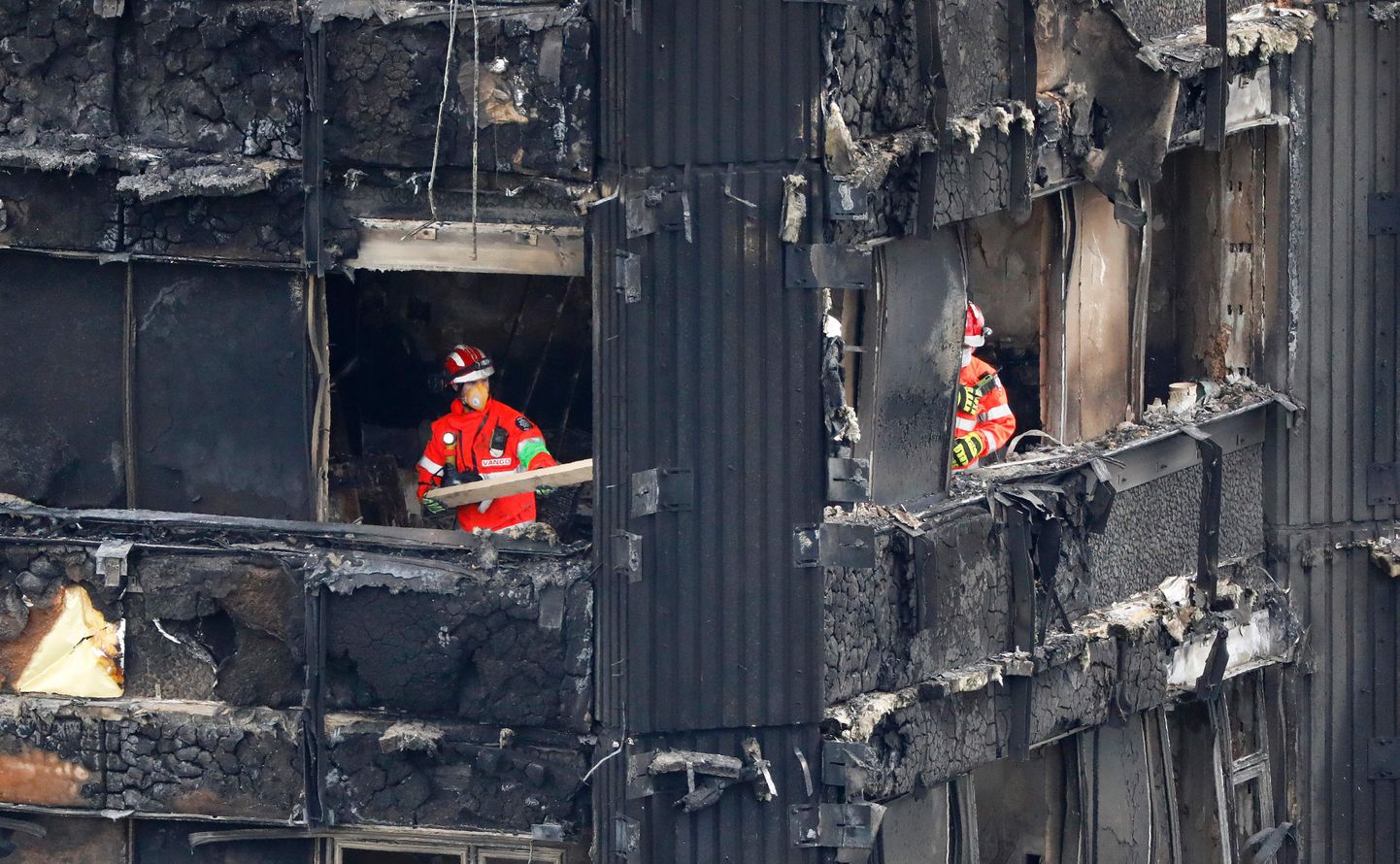 TOPSHOT - Members of the emergency services work on the middle floors of the charred remnains of the Grenfell Tower block in Kensington, west London, on June 17, 2017, follwing the June 14 fire at the residential building.
Angry London residents heckled Prime Minister Theresa May and stormed local authority headquarters Friday as they demanded justice for the victims of the June 14 Kensington tower block fire that left 30 people dead, with dozens more unaccounted for. / AFP PHOTO / Tolga AKMEN