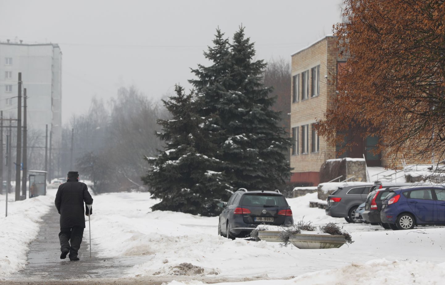 Vīrietis uz ledainās ietves pie Rīgas sociālās aprūpes centra "Gaiļezers".