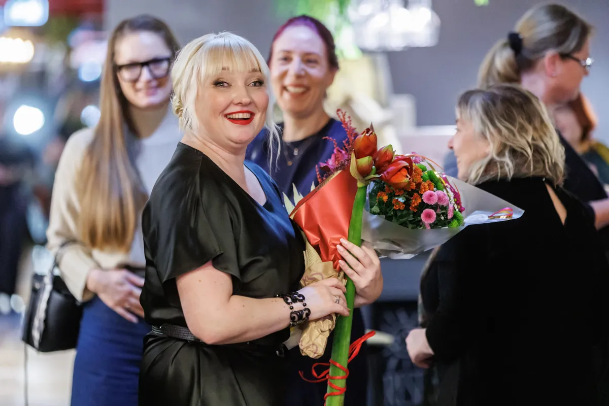 Evelin Ojamets võtab vastu lillesülemeid ning õnnesoove. Tagaplaanil paistavad Karin Järvet ning Anne Rinne.