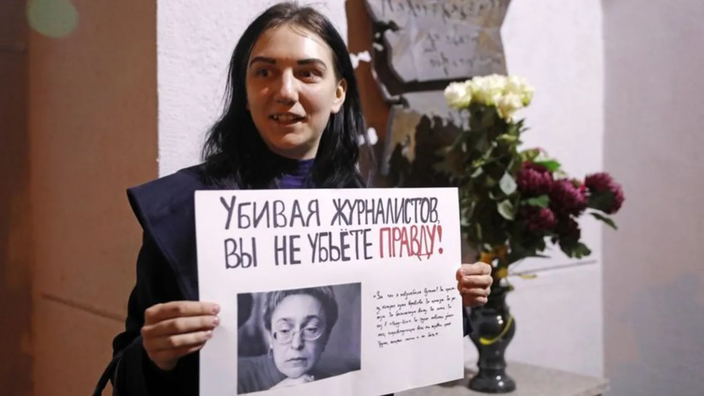 Девушка с плакатом у мемориальной доски в честь журналистки Анны Политковской на здании редакции "Новой газеты" в Москве. Политковская была убита 7 октября 2006 года