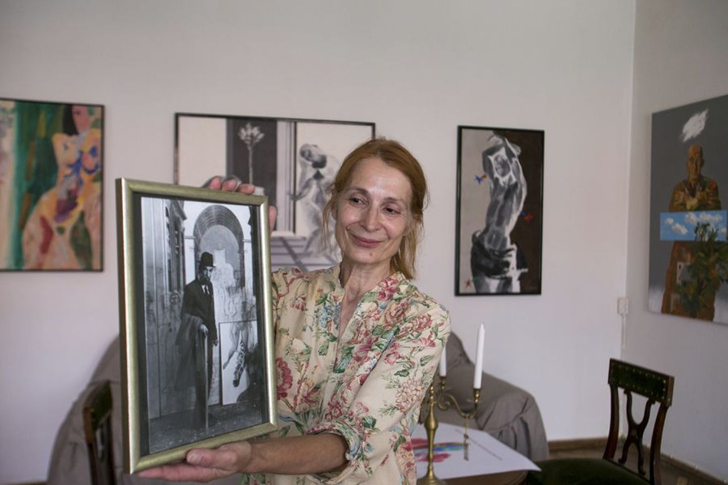 Enn Põldroosi eramuuseumi tegevjuht Rita Raave näituseruumis koos kunstniku noore aja pildiga