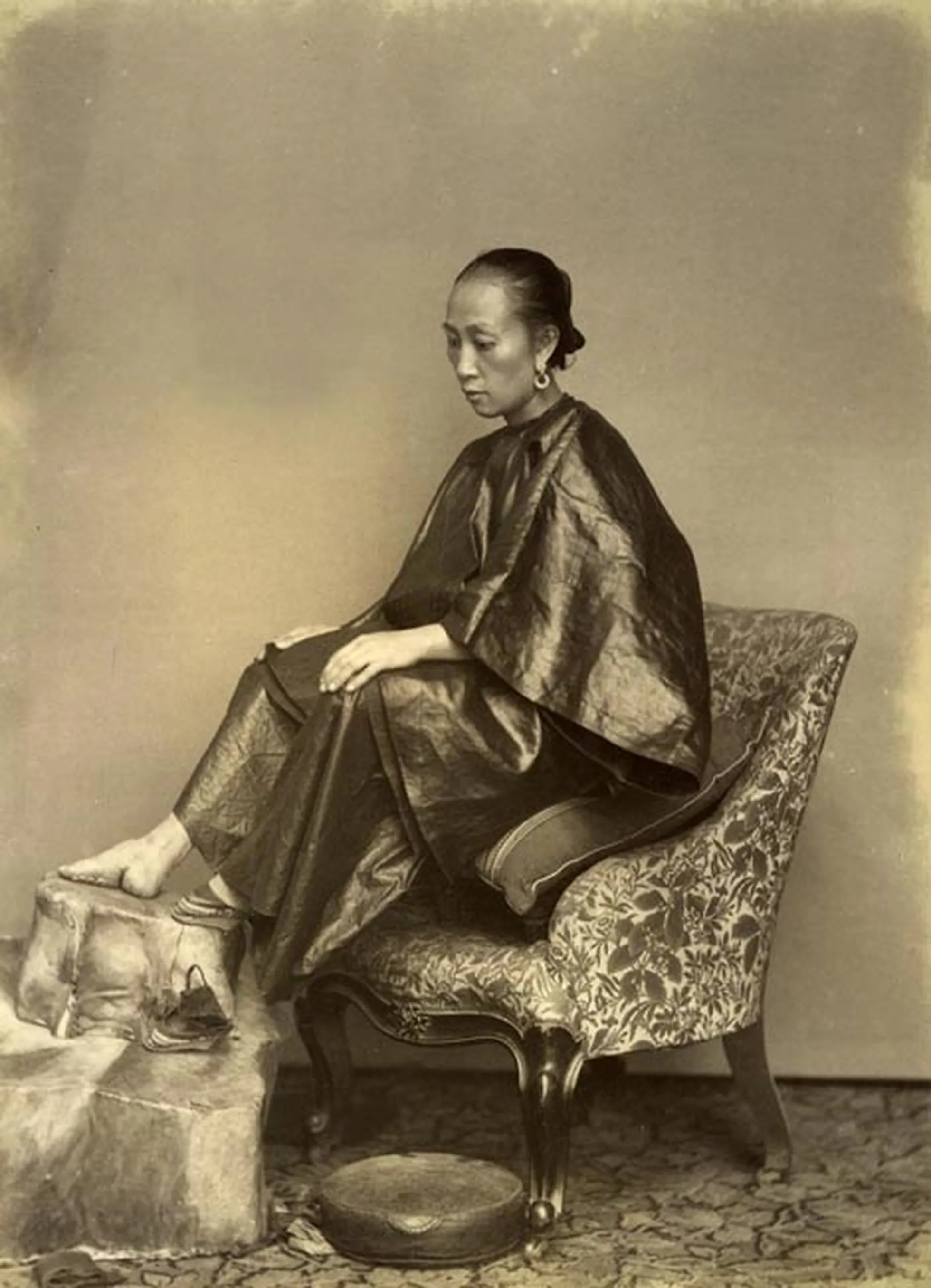 Hiina naine oma köidetud jalga näitamas, foto tehtud umbes 1870. aastal.