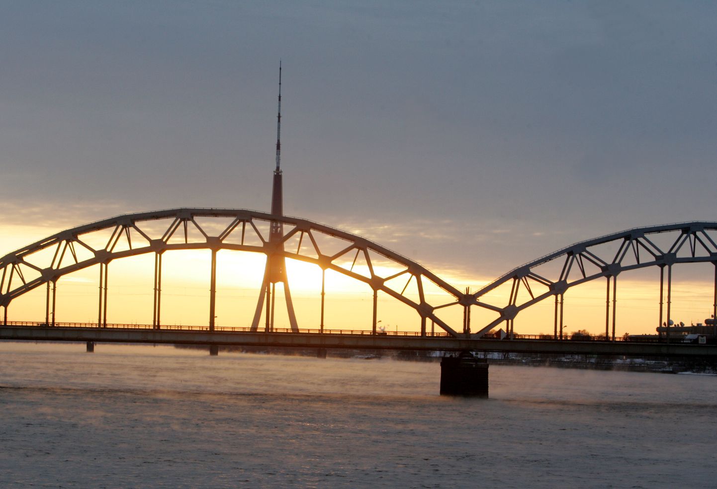 Dzelzceļa tilts un saullēkts virs Daugavas.