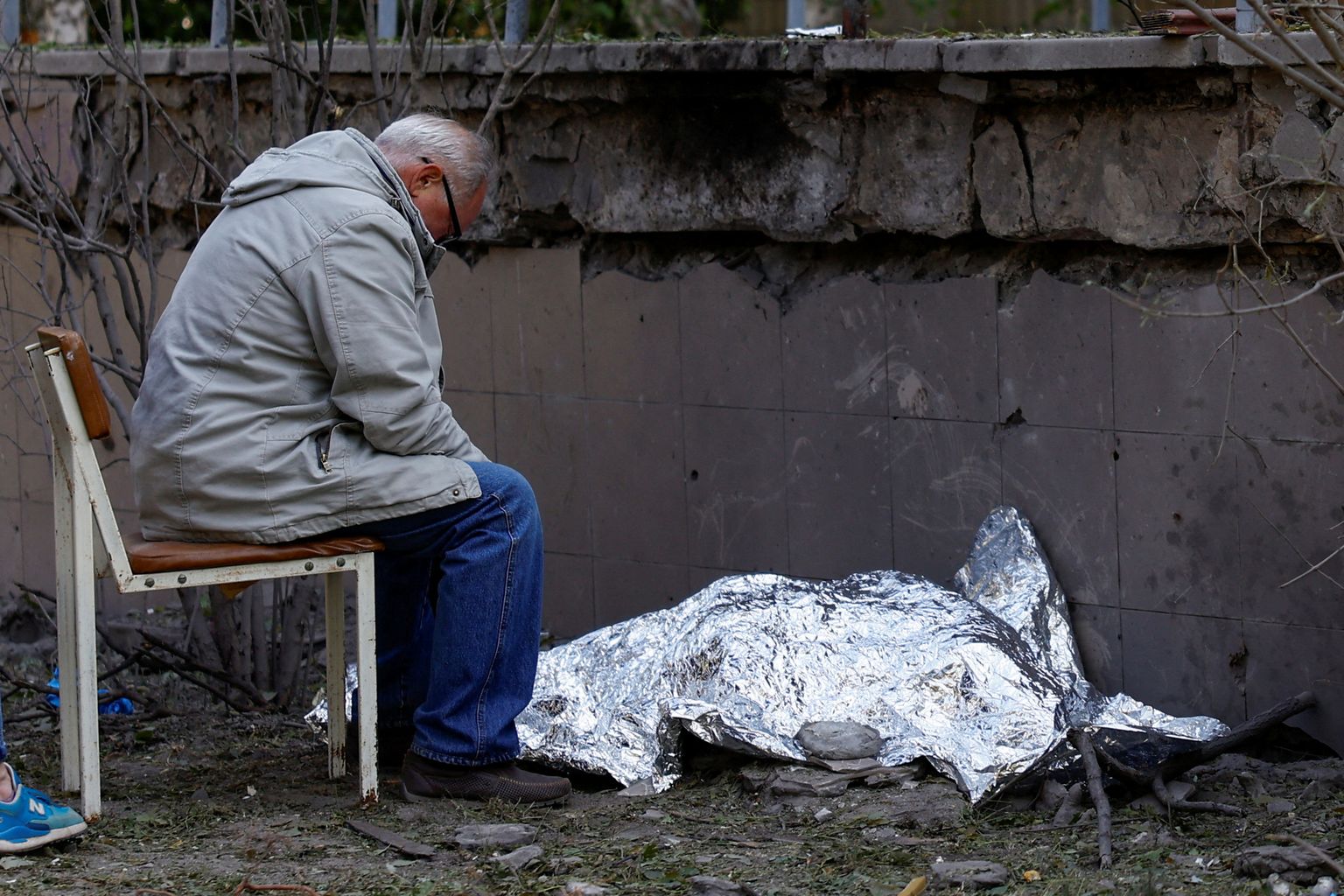 Мужчина сидит рядом с телом своей внучки, которая была убита во время российского ракетного удара по Киеву, Украина, 1 июня 2023 года.