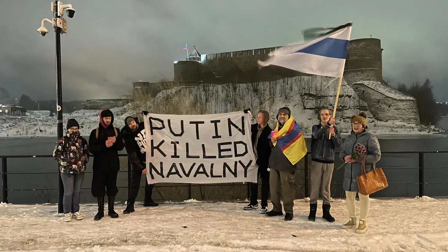 Участники акции в память об Алексее Навальном на берегу пограничной реки Нарва. Плакат в их руках прямо обвиняет Путина в убийстве политического оппонента.
