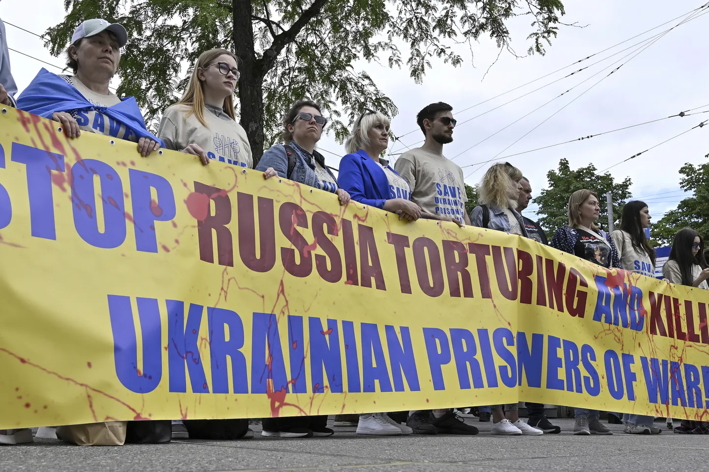 Protestijad plakatiga, millel on kirjas «Peatage Venemaa Ukraina sõjavangide piinamisel ja tapmisel» Šveitsi linnas Luzernis 15. juunil 2024. aastal.