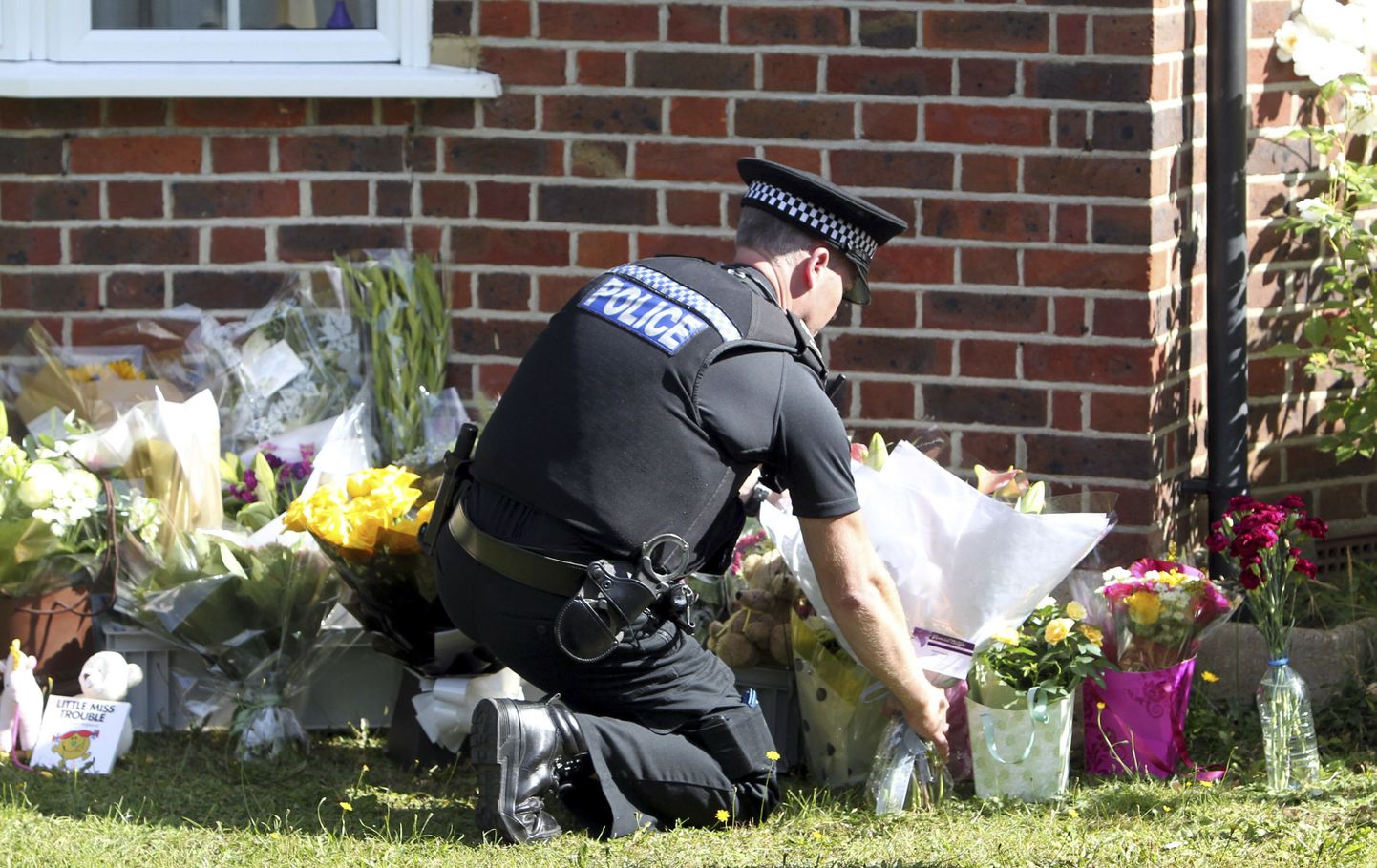 Briti politseinik asetamas lilli mõrvatud iraaklaste kodu juurde Claygate'is.