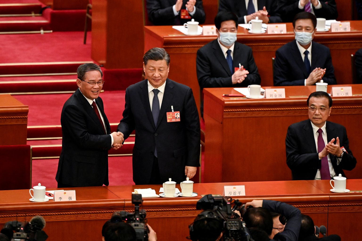 Hiina president Xi Jinping surub kätt oma ühel ustavamal liitlasel, vastselt ametisse vannutatud peaministril Li Qiangil, all paremal aplodeerib ametist lahkuv Li Keqiang.