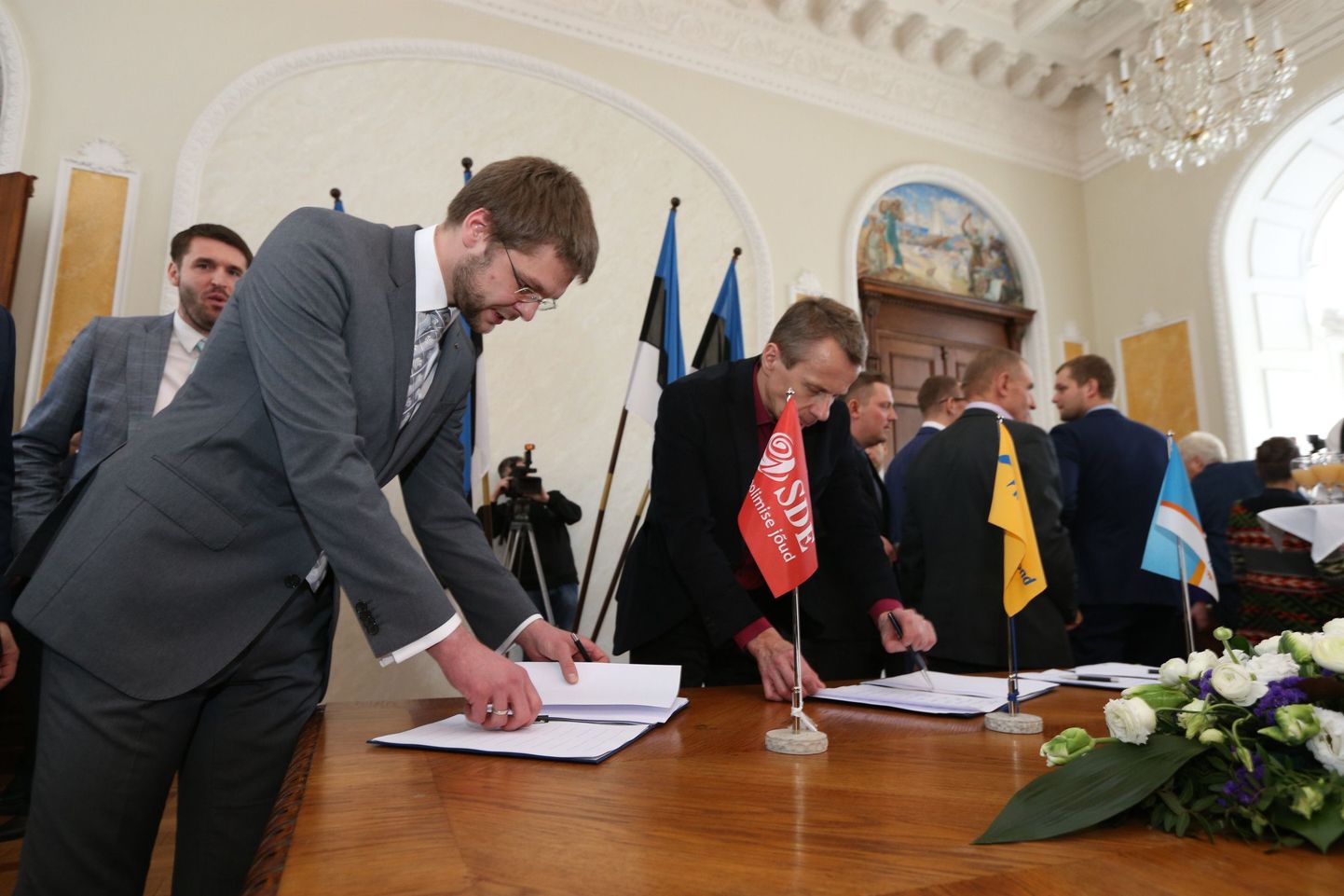 Jevgeni Ossinovski (SDE) ja Jürgen Ligi (RE) 2015. aastal koalitsioonileppele allkirju andmas. 2014. aastal astus Ligi rahandusministri ametist tagasi, sest oli nimetanud Ossinovskit «sisserändaja pojaks».