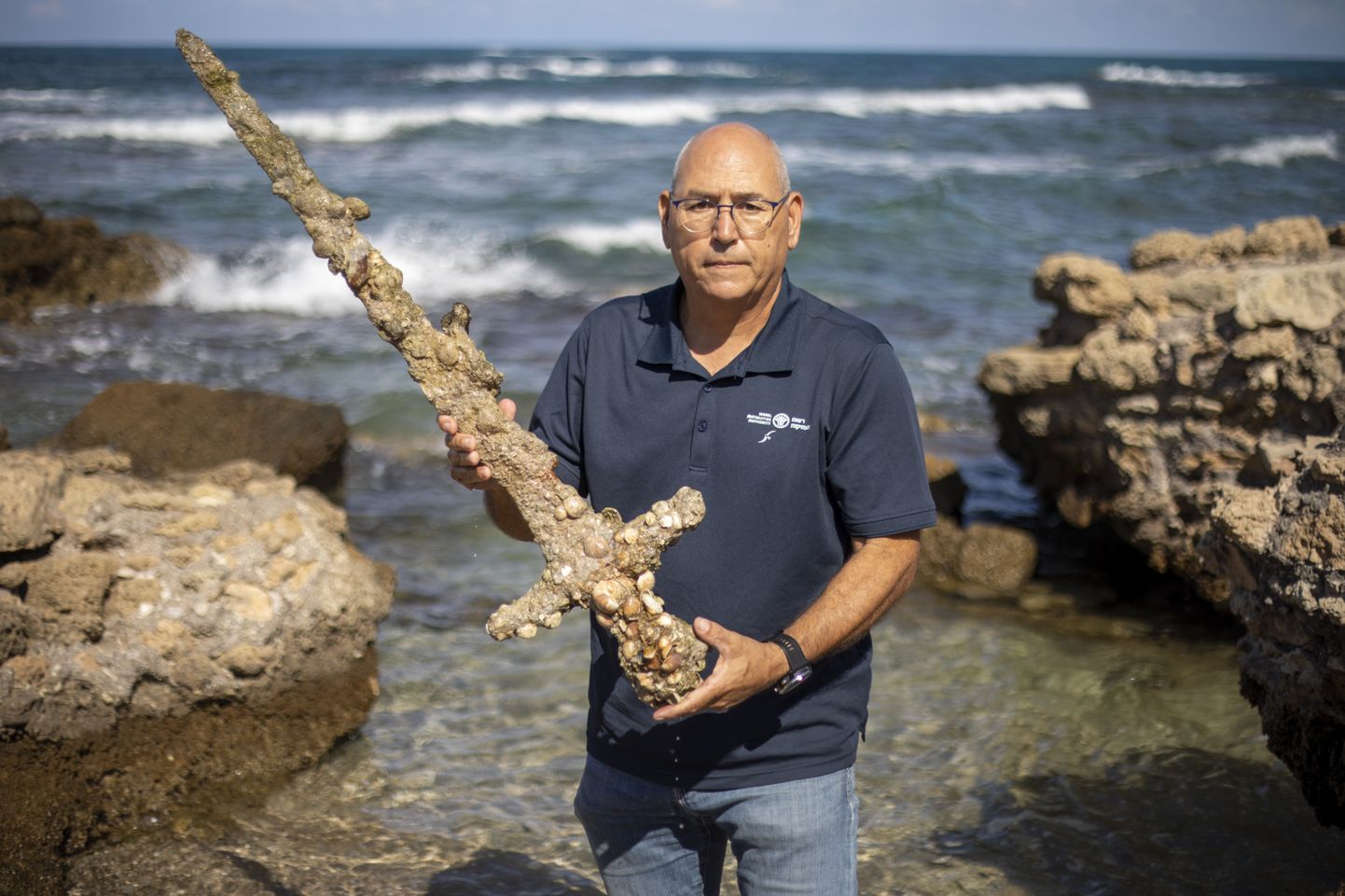 Iisraeli antiigiameti merearheoloogia üksuse direktor Jacob Sharvit hoidmas 19. oktoobril 2021 Iisraelis Vahemere sadamas Cesareas käes meetripikkust mõõka, mis ekspertide sõnul pärineb ristisõdijate ajast
