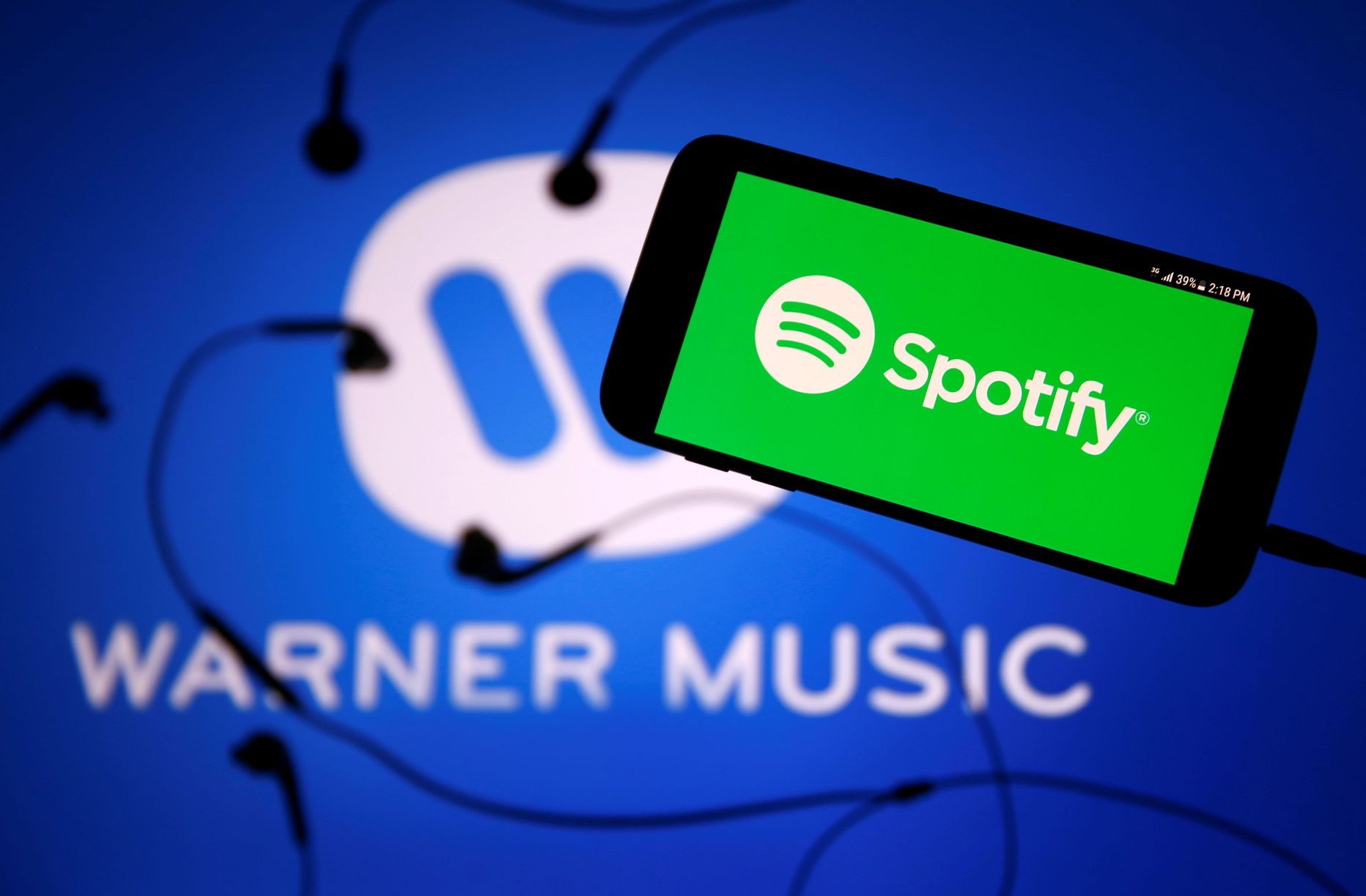 A smartphone with a headset with Spotify logo are seen in front of a displayed Warner Music logo in this illustration picture taken July 24, 2017. REUTERS/Dado Ruvic