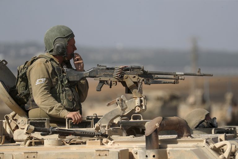 Израильский солдат около пулемета на башне танка в районе границы с сектором Газа, юг Израиля, 13 октября 2023 года.