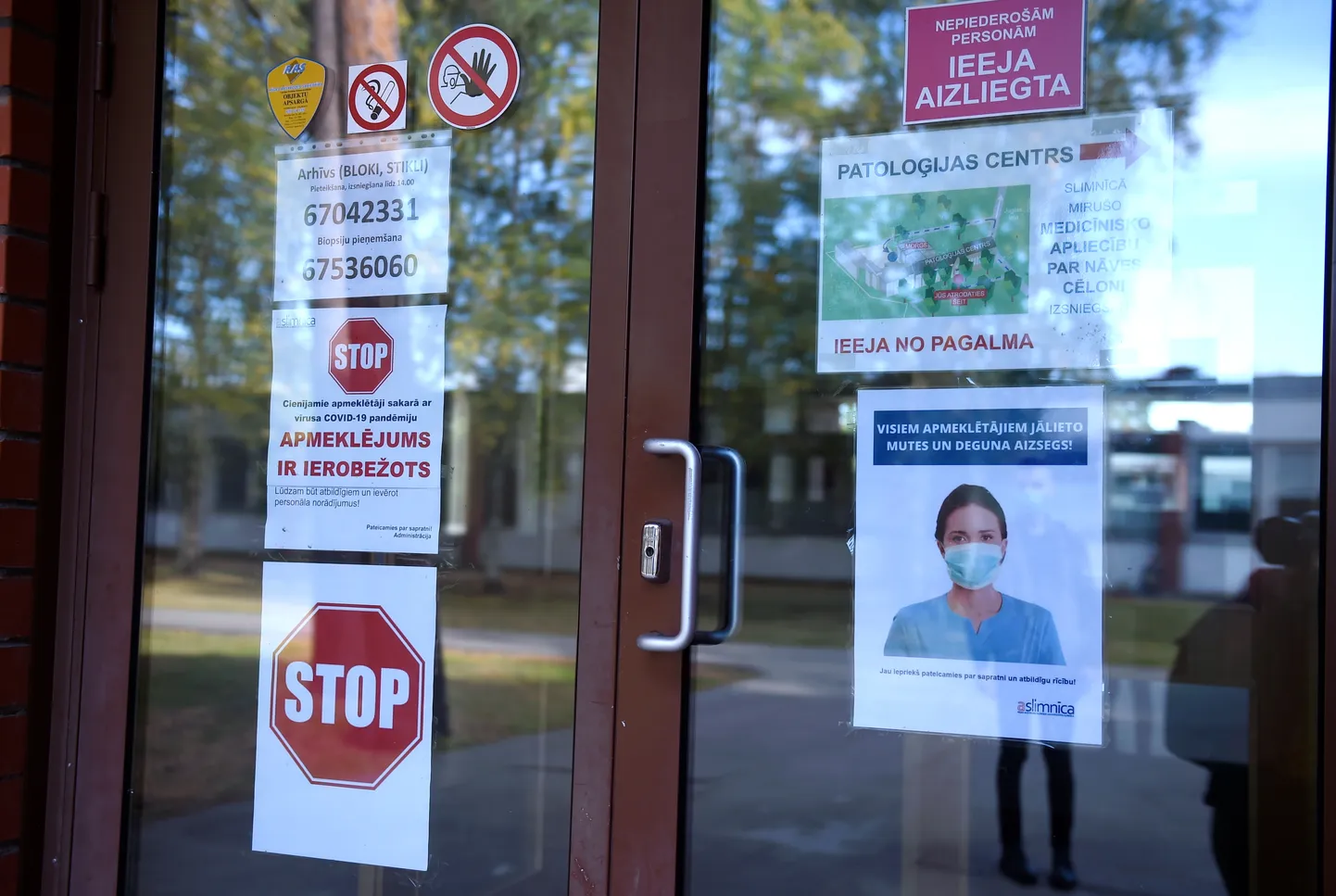 Uzraksti Covid-19 vīrusa laikā pie SIA "Rīgas Austrumu klīniskā universitātes slimnīca" Patoloģijas centra durvīm.