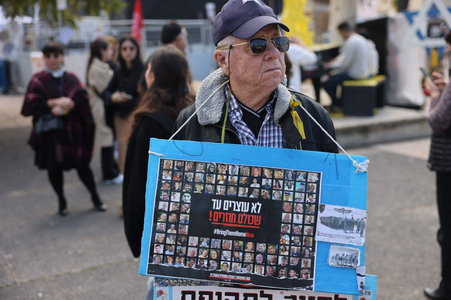 Tel Avivi tänaval seisev mees kannab kaelas plakatit piltidega pantvangidest, kelle Hamas röövis oktoobris.