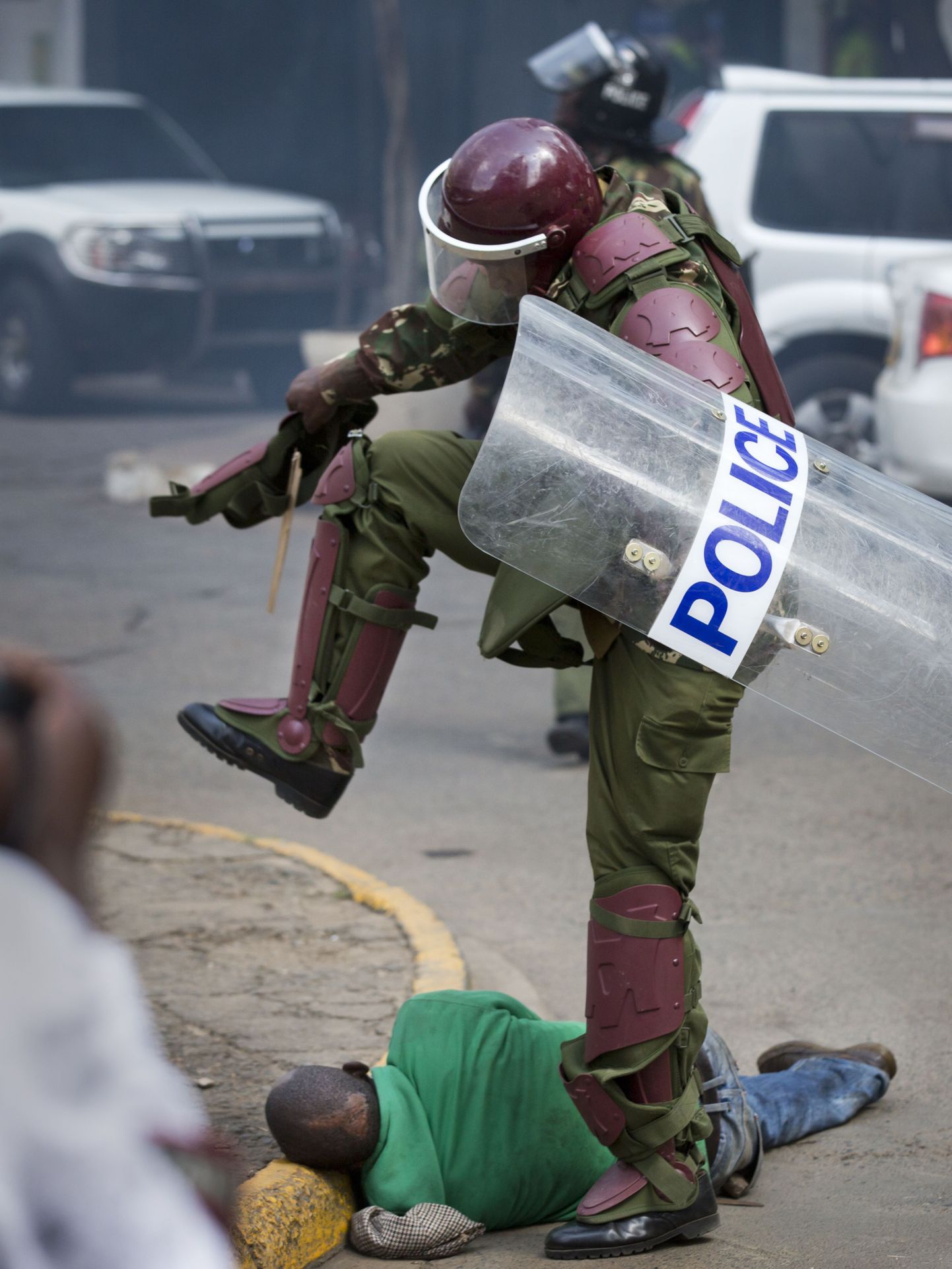 Keenia märulipolitseinik maas lamavat meest löömas. Pilt on illustratiivne