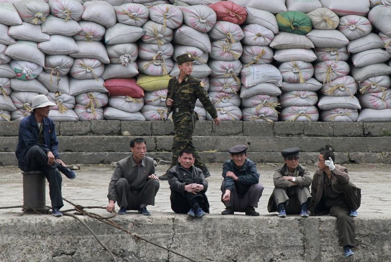 Põhja-Korea sõdur möödub meestest, kes puhkavad jalgu kaupu täis kottide ees Yalu jõe kaldal, Hiina piirilinna Dandongi vastas.