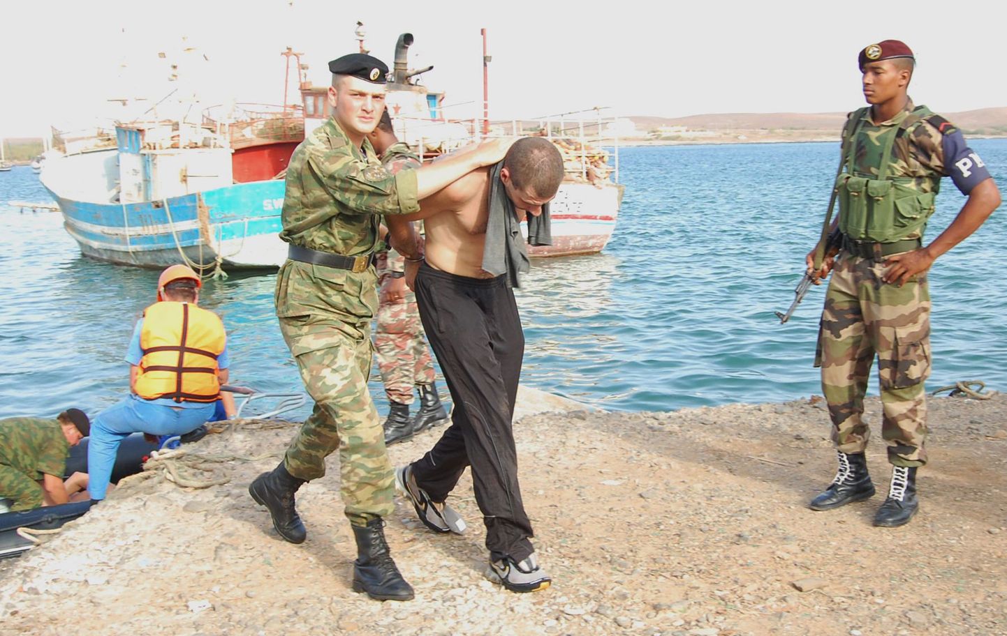 Vene mereväelased toimetavad väidetavad kaaperdajad laevalt maale.