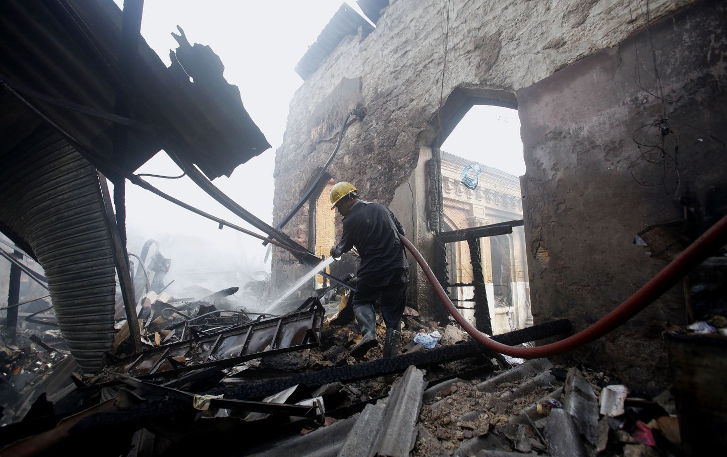 Illustreerival fotol kustutab tuletõrjuja tänavu märtsis Karachit tabanud suurpõlengus hävinud poe varemeid.