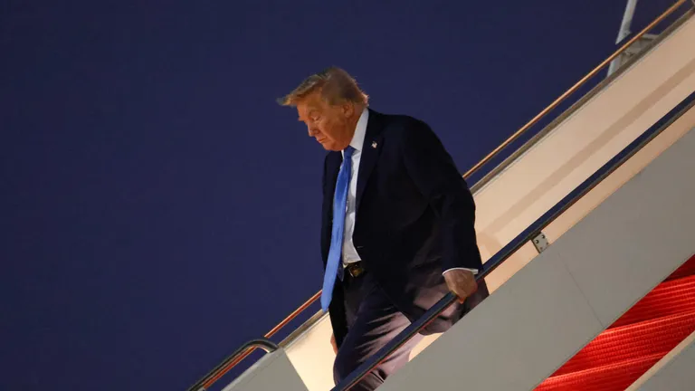 Трамп сходит по трапу самолета после возвращения в США