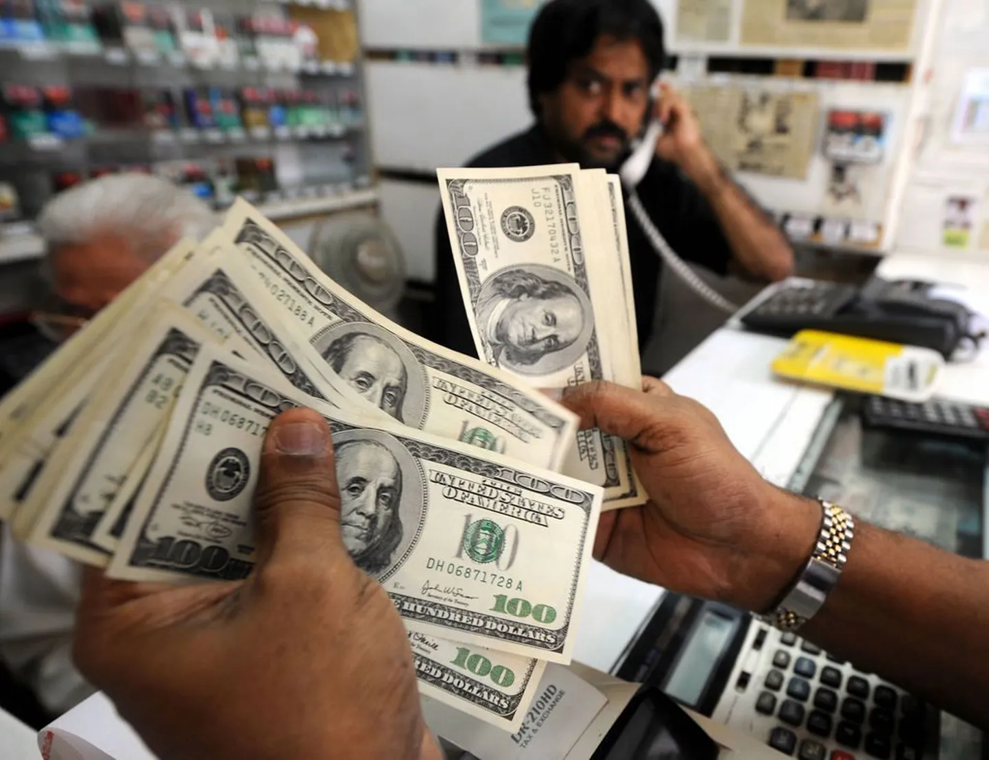 100-dollarilised rahatähed valuutadiileri käes.
