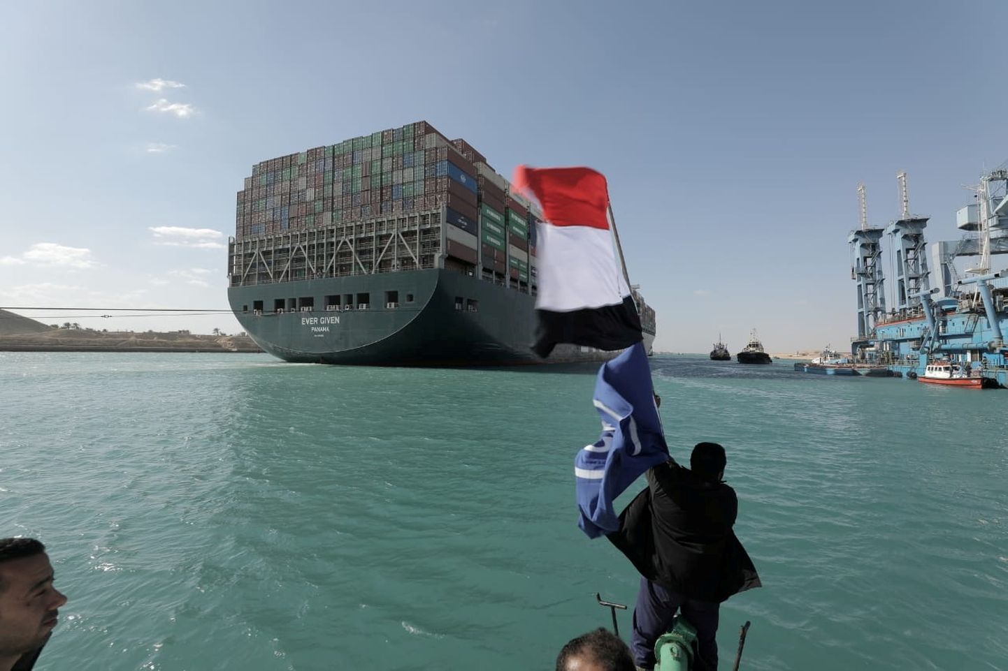 Mees lehvitab Egiptuse lipuga konteinerilaevale Ever Given pärast aluse lahti päästmist madalalt Suessi kanalis 29. märtsil. Hetkel seisab laev kanali keskosas Suurel Mõrujärvel ja ootab Egiptuse võimude luba lahkumiseks.