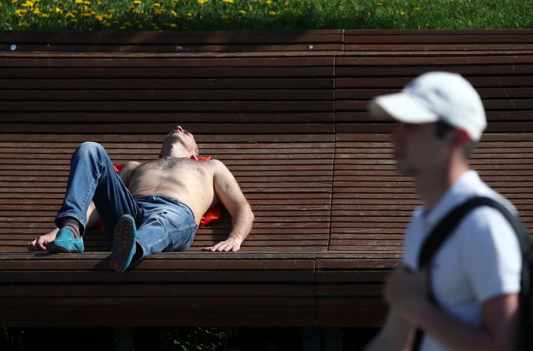 Мужчина лежит на скамейке у Москвы-реки. 17 мая 2021 г.