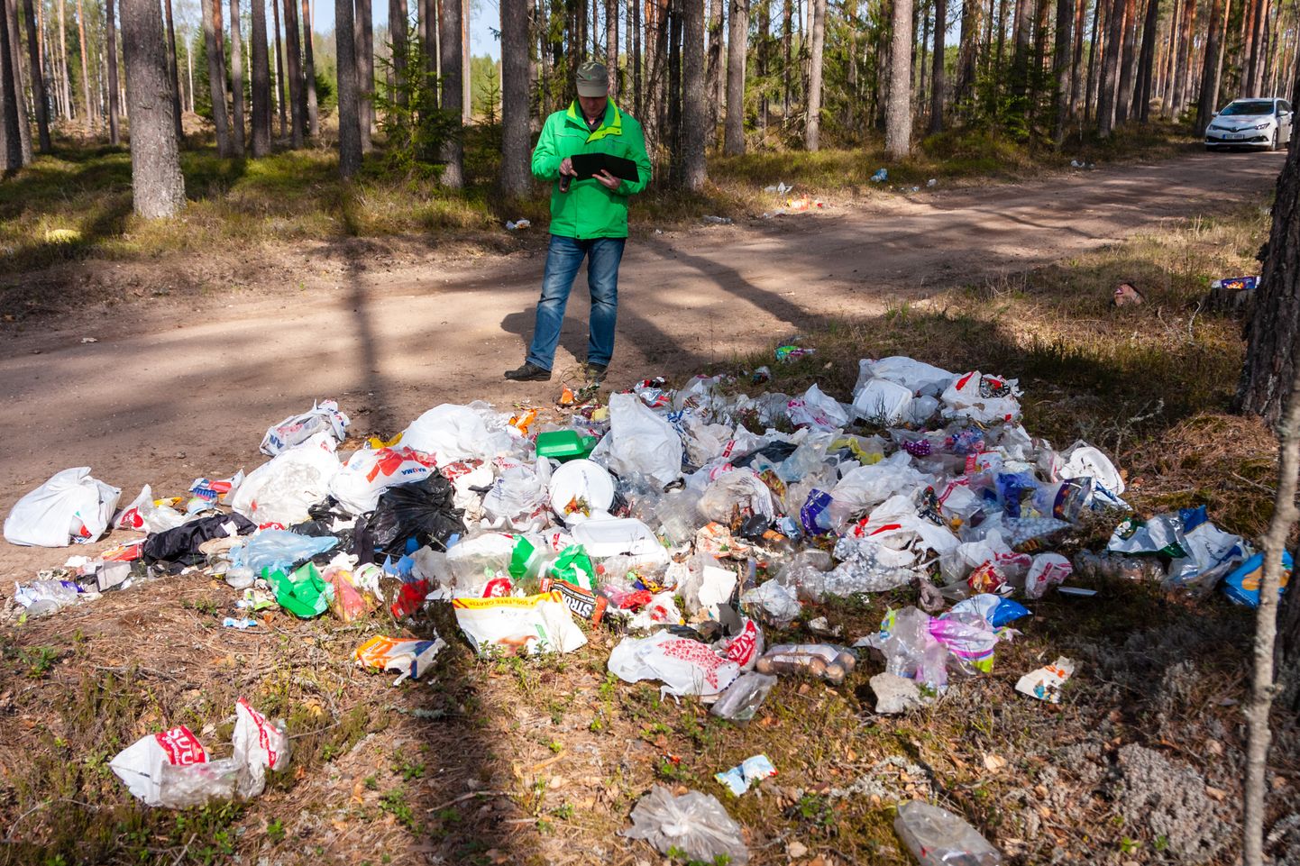 Prügi viiakse hoolimatult loodusesse. Pildil on näha peamiselt pakendijäätmete prügihunnikut Valgast 11 km kaugusel Koiva külas. Metsaülem Risto Sepp jäädvustab asupaika, et korraldada jäätmete koristus ja äravedu.