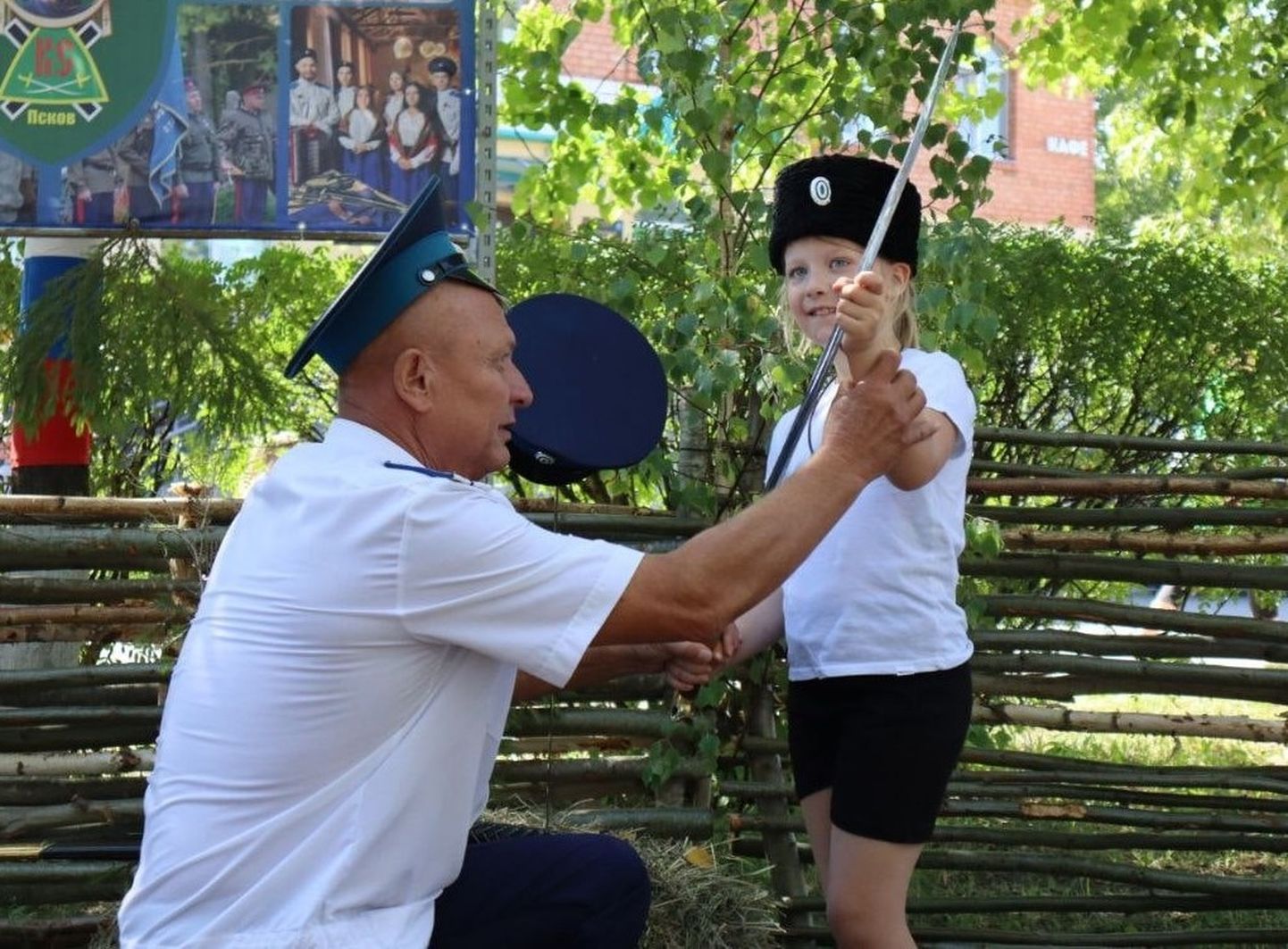Псковский "казак" учит девочку держать в руке саблю, Струги Красные, Псковская область, 2023 год.