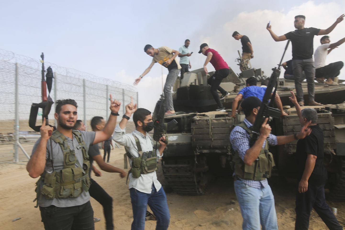 Hamasi võitlejad juubeldamas hävitatud Iisraeli tanki juures Gaza piiritara juures 7. oktoobril 2023. aastal.