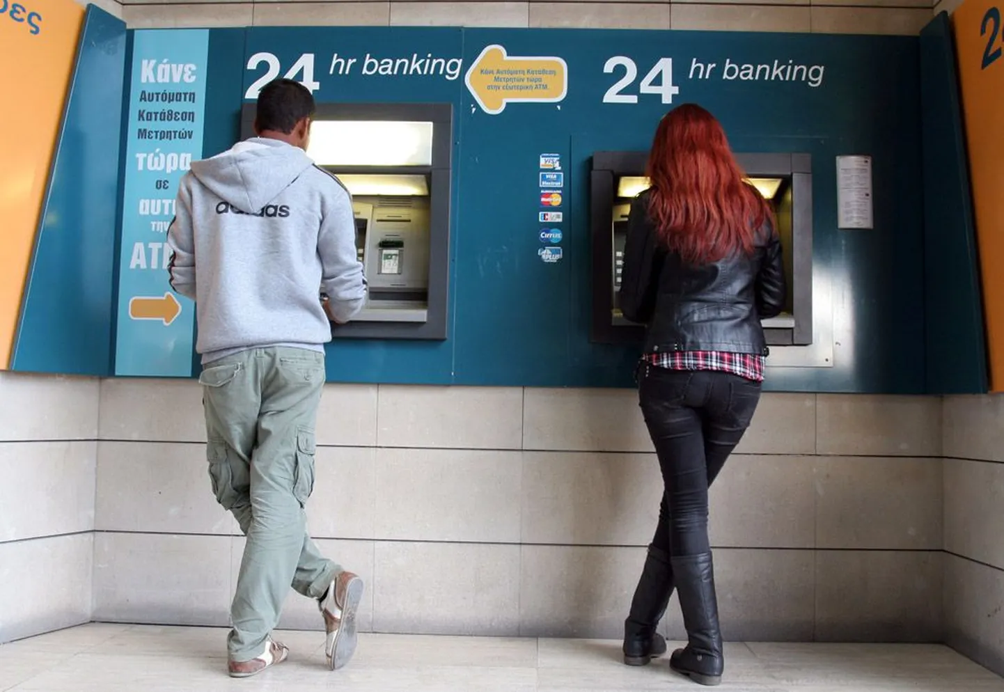 Mees ja naine üleeile Küprose pealinnas Nicosias sularahaautomaadist raha välja võtmas. Kuigi ühekordne pangamaks ei ole veel jõustunud, on pangad juba kontoomanikelt vastava summa blokeerinud.