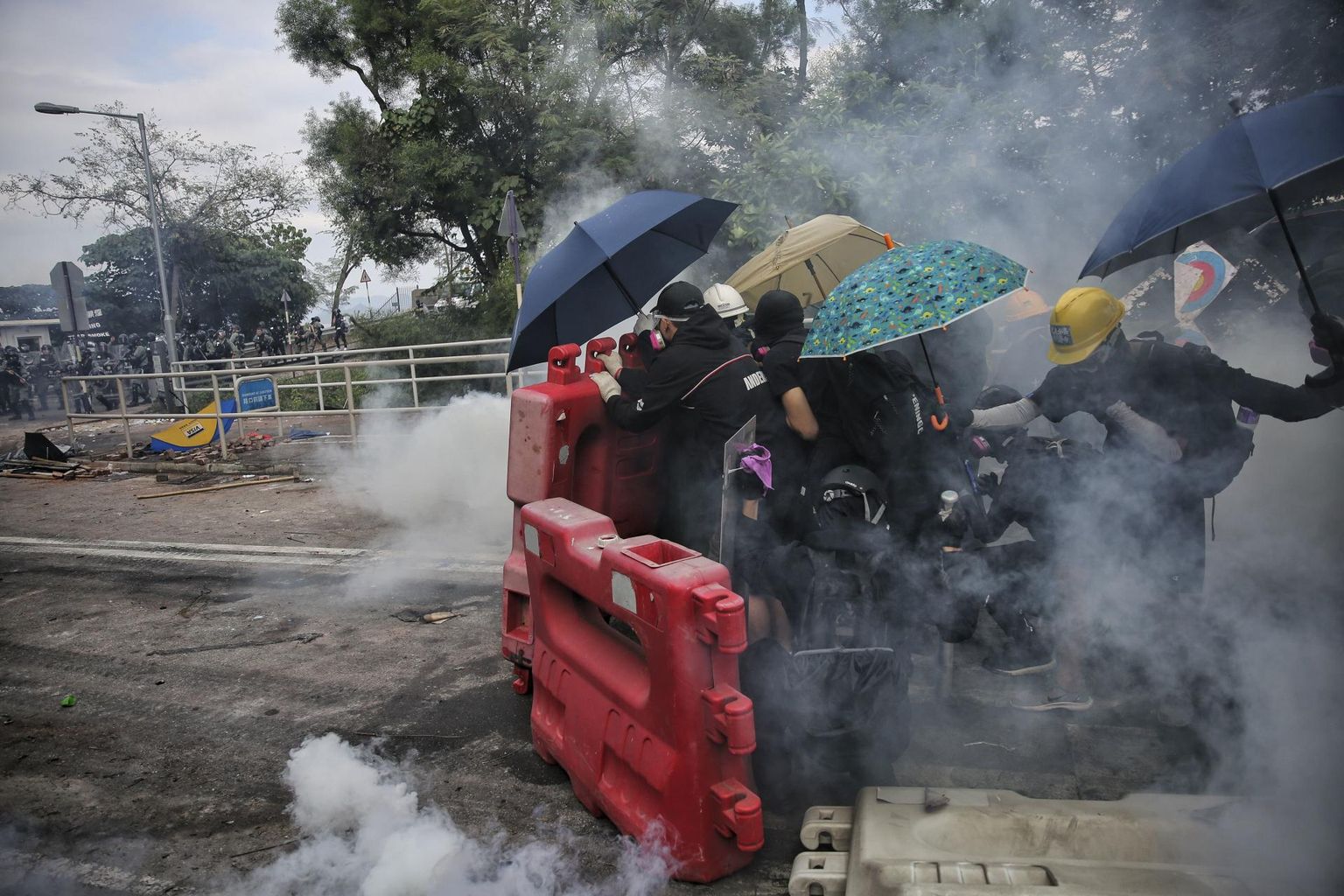 Üliõpilased varjuvad pisargaasi eest barrikaadide ja vihmavarjude taha.