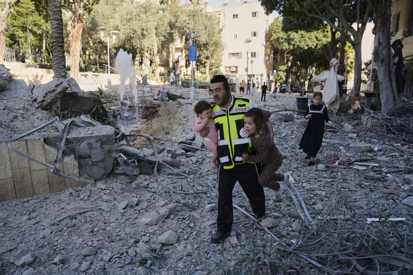 Päästetöötaja evakueerib kahte last sündmuskohalt, kus Iraanist välja lastud rakett tabas Iisraeli Haifa linna pühapäeval, 22. juunil 2025.