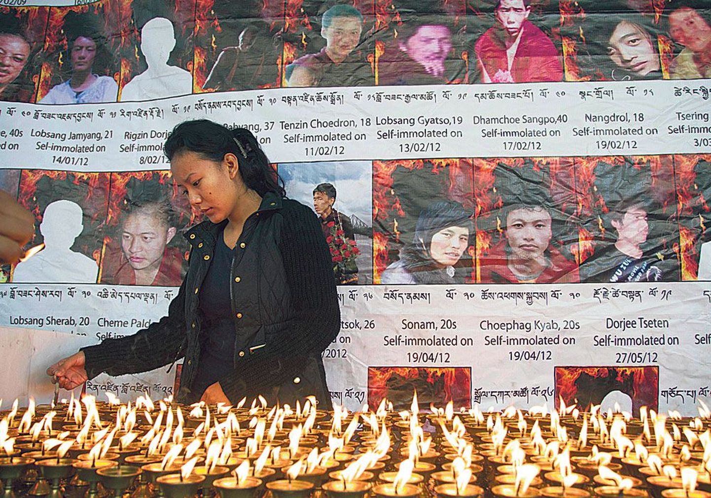 В городе Дарамсале, расположенном в Северной Индии, жительница Тибета, находясь в изгнании, зажигает свечи перед фотографиями тибетцев, которые подожгли себя в знак протеста против китайских властей.