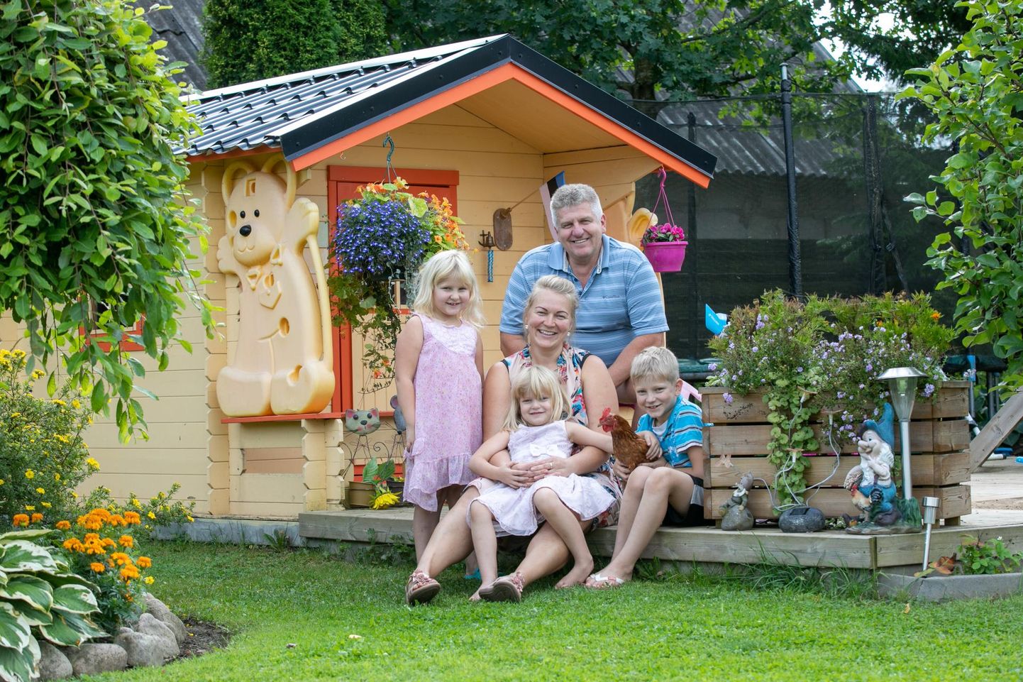 Angela ja Arno Pilt oma koduaias mängumaja terrassil koos nooremate laste Adeele (vasakult), Arete ja Andriga, kes hoiab süles kana Roosit. “Kodus peab olema kõigil hea,” ütleb pereisa.