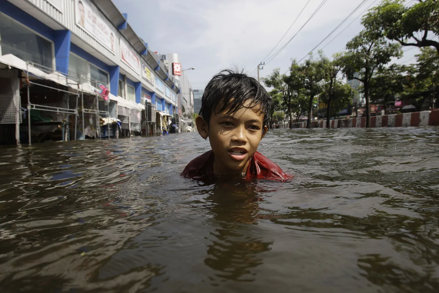 Тайский мальчик плывет по затопленной улице.