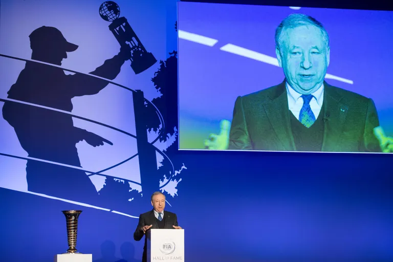 Jean Todt rääkimas kuulsuste halli avatseremoonial, taustal Michael Schumacheri siluett.
