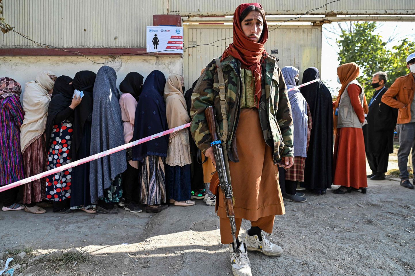 Talibani võitleja valvab Kabulis, kui naised seisavad laupäeval järjekorras, et saada Maailma Toiduprogrammi abipakke.