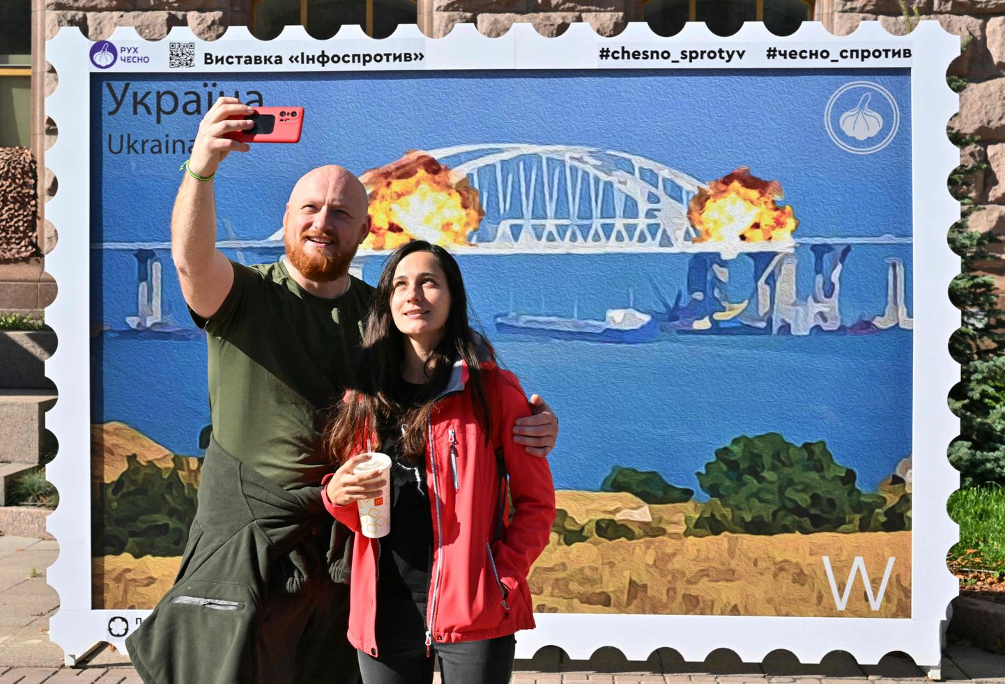 Киевляне стоят перед стрит-артом, изображающим взрыв Керченского моста. Снимок иллюстративный.