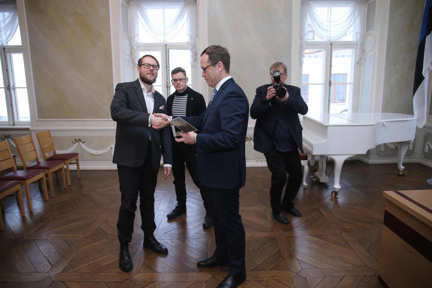 Tartu raekoja kellad löövad keskpäevatundi, kui linnapea Urmas Klaas uut linnakirjanikku Vahur Afanasjevit (vasakul) stipendiumi saamise puhul õnnitleb.