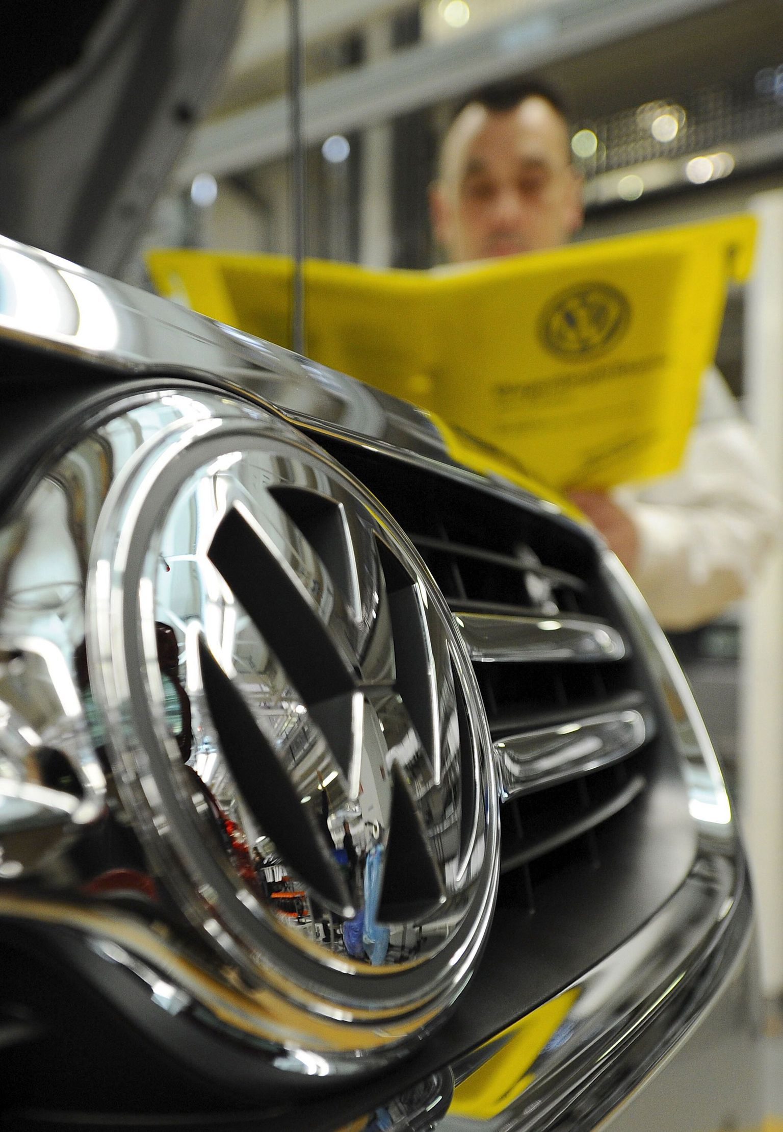 Saksa autotootja Volkswageni tööline seismas uue auto kõrval Wolfsburgi tehases.