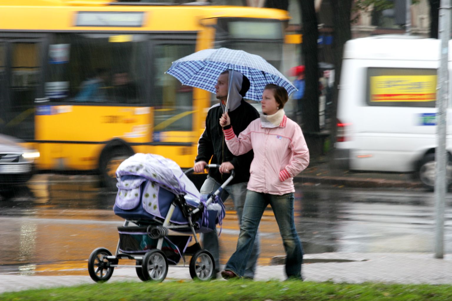 Ģimene ar bērnu ratiņiem lietus laikā.