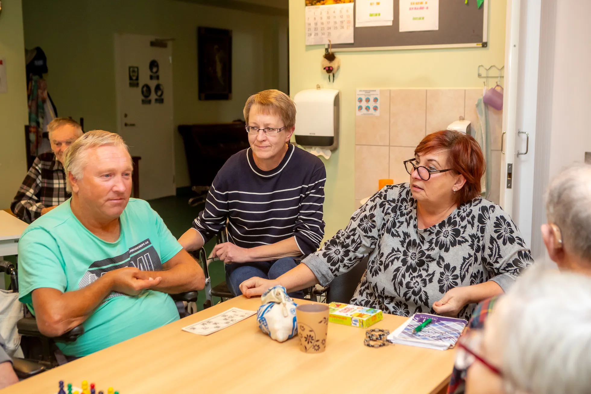 MÄNGULAUA ÄÄRES: Intervallhoolduse klient Heino Miilits, hooldekodu juhataja Kaire Tiik ja tegelusjuhendaja Jaanika Rikko.