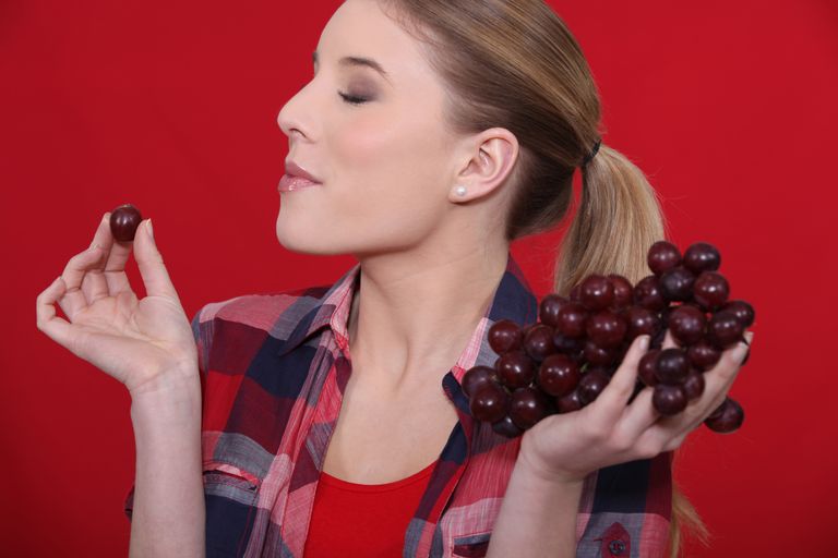 Naine söömas punaseid viinamarju. Pilt on illustreeriv