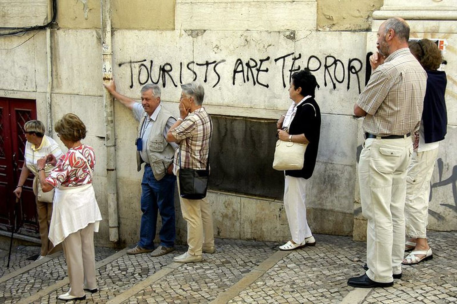 Lissabonis majaseinale kirjutatud arvamusavaldus turistide kohta.