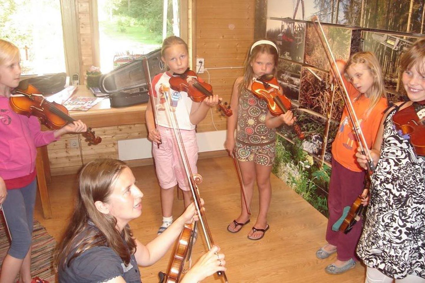 Viiulimängu õppimine 2009. aasta rahvamuusikalaagris Kablis. Viiulimänguga on alustamas Mirjam, Anna-Liisa ja Carolyn. Esiplaanil õpetaja Kristi Alas.