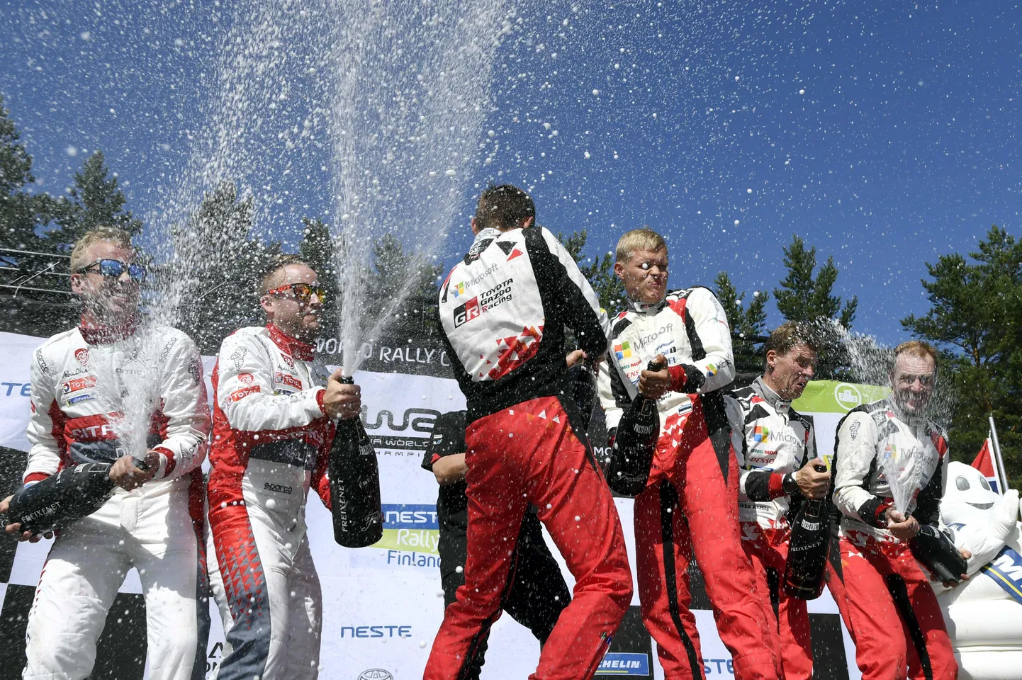 Mads Östberg (vasakult teine) pritsimas 2018. aasta Soome rallil šampust, temaga jagavad poodiumi Ott Tänak–Martin Järveoja ning Miika Anttila–Jari-Matti Latvala.