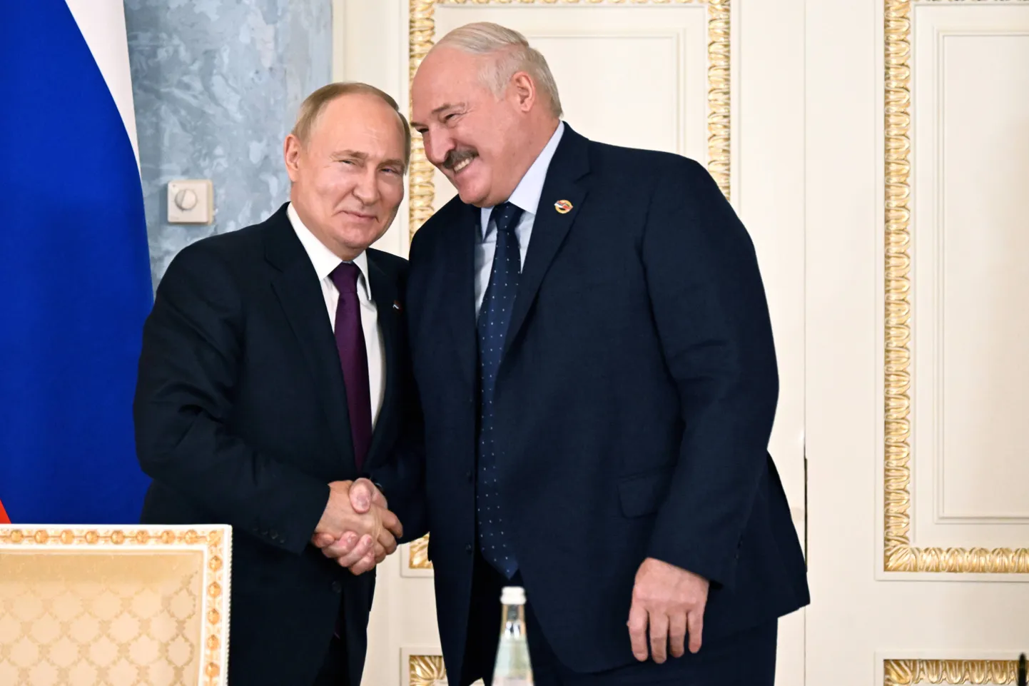 Лукашенко смеется и пожимает руку Путину, январь 2024 года, Санкт-Петербург, Россия.