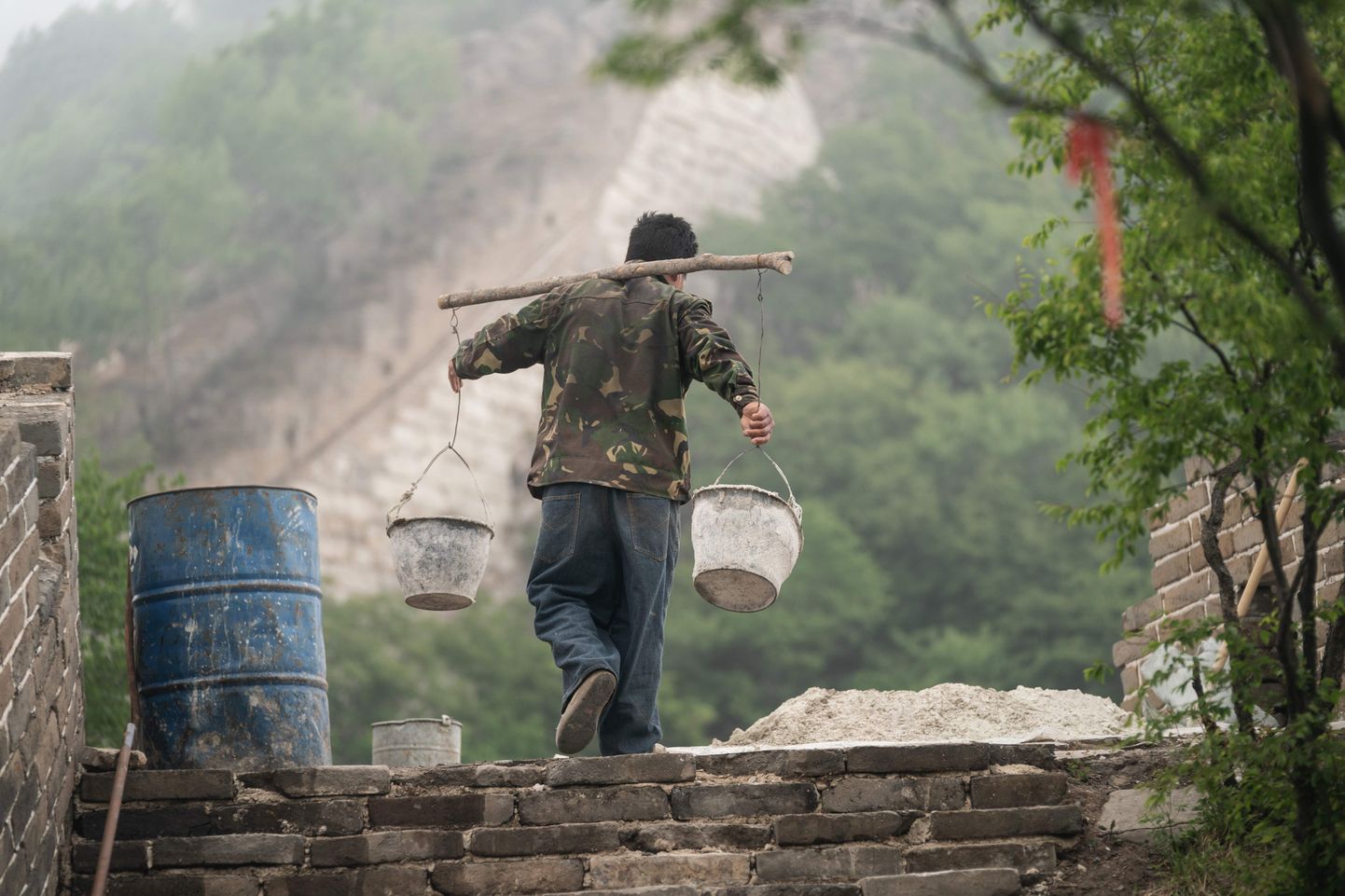 Tööline kannab ämbreid Hiina müürile.