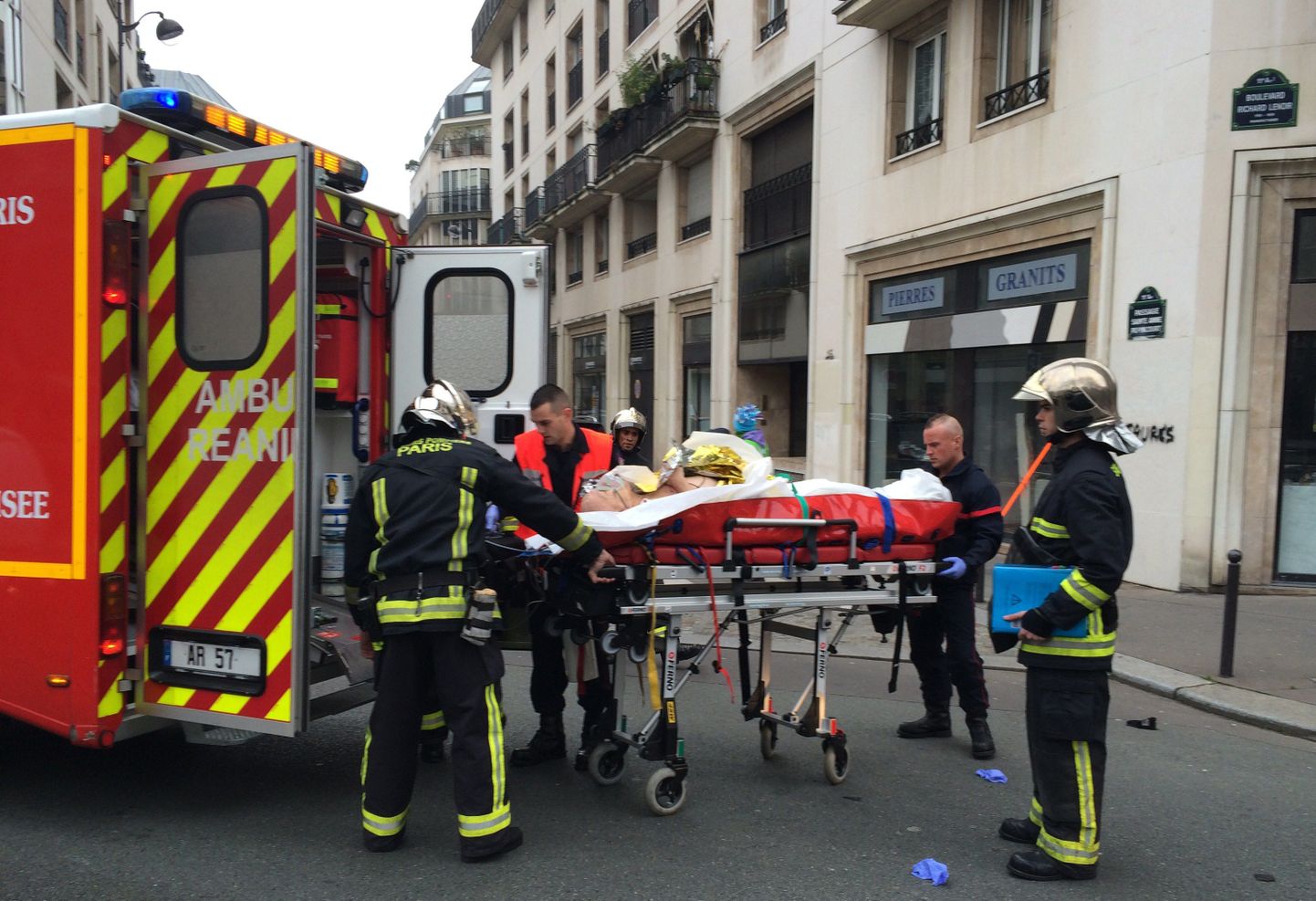 Tuletõrjujad kannavad haavatut välja satiirilise nädalalehe Charlie Hebdo toimetusest Pariisis.