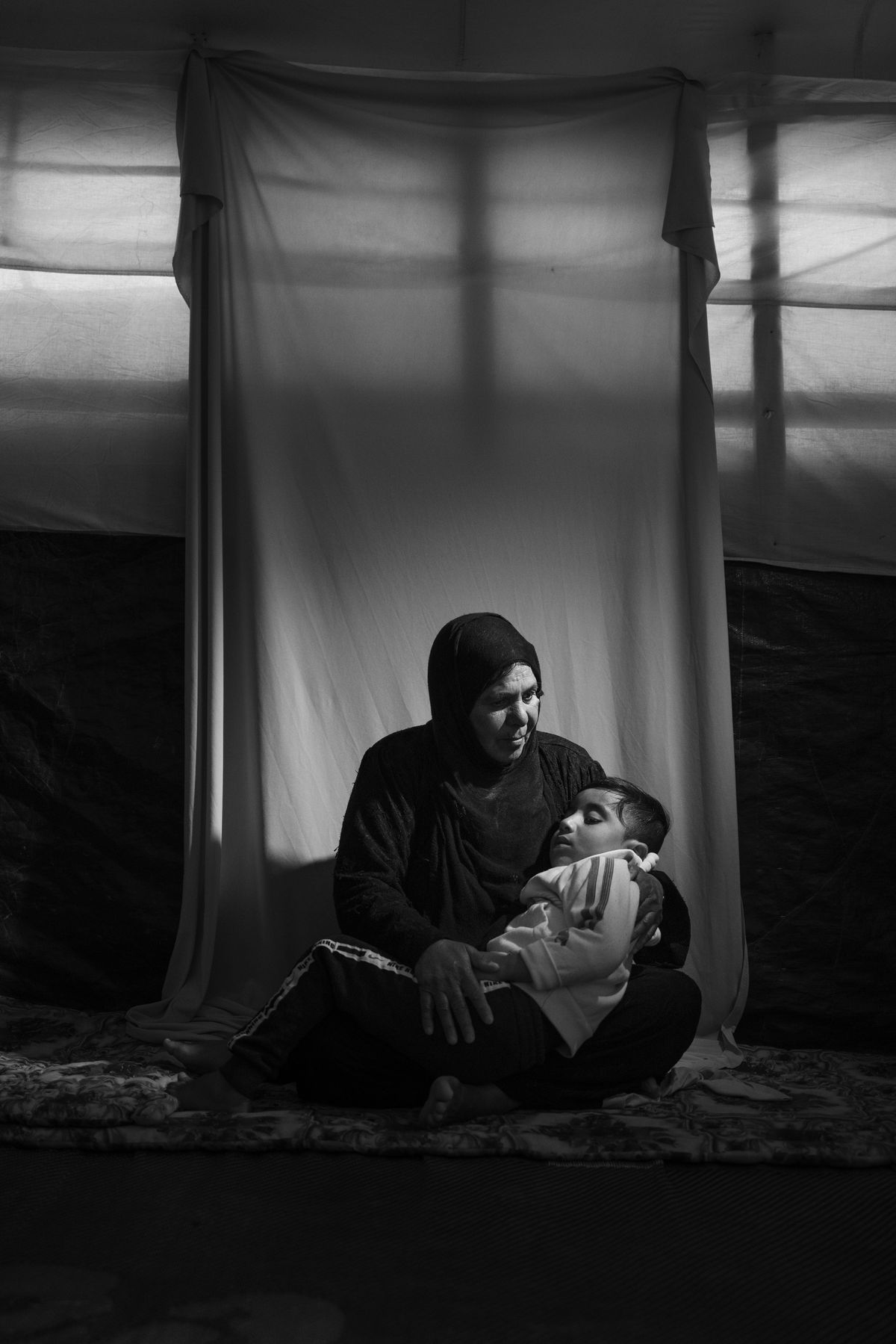 Noora Ali Abbas (60) istub koos lapselaps Harrethiga (6) oma telgis Salamiyah laagris, Iraagis Ninevehis. Noora ütleb, et Harrethi isa rööviti ISISe poolt 2015. aastal, kuid Harreth on kodakontsusetu ja ei saa Iraagi isikutunnistust, kuna ametivõimud usuvad, et tema isa oli ISISe võitleja.